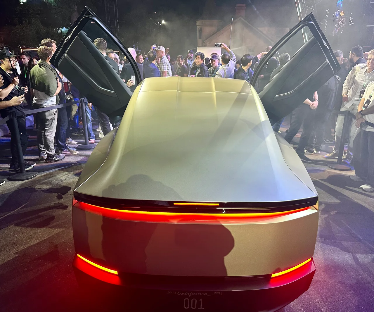 Rear of a gold Tesla Cybercab concept with both doors raised at its 2024 unveiling